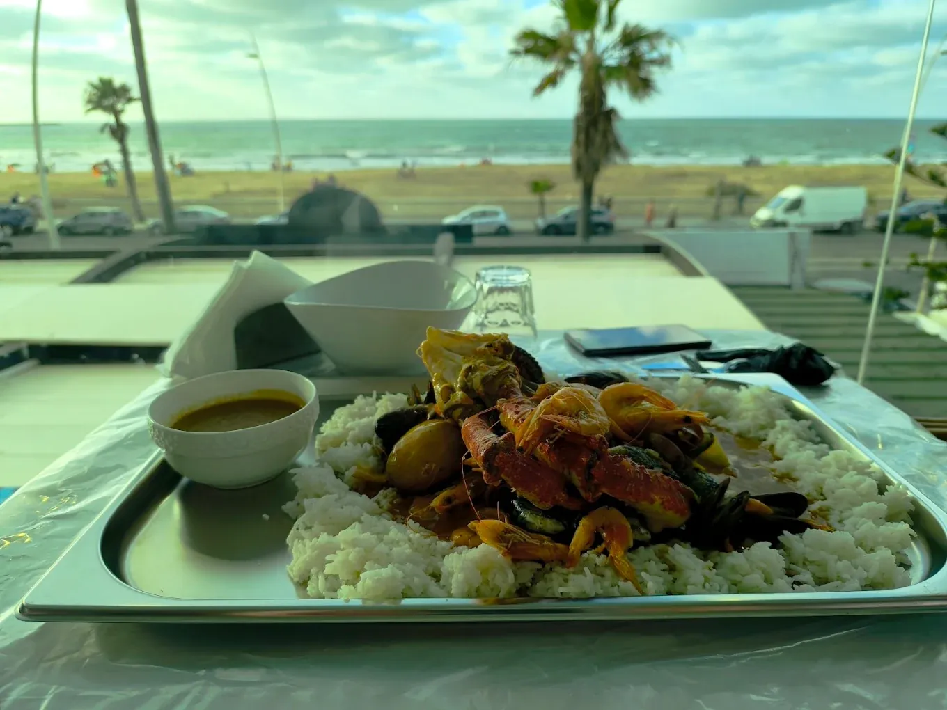 Seafood Boil de Mucho : crevettes, crabe et moules sur riz, sauce Old Bay à part, servi face à la plage et à l'océan d'El Jadida
