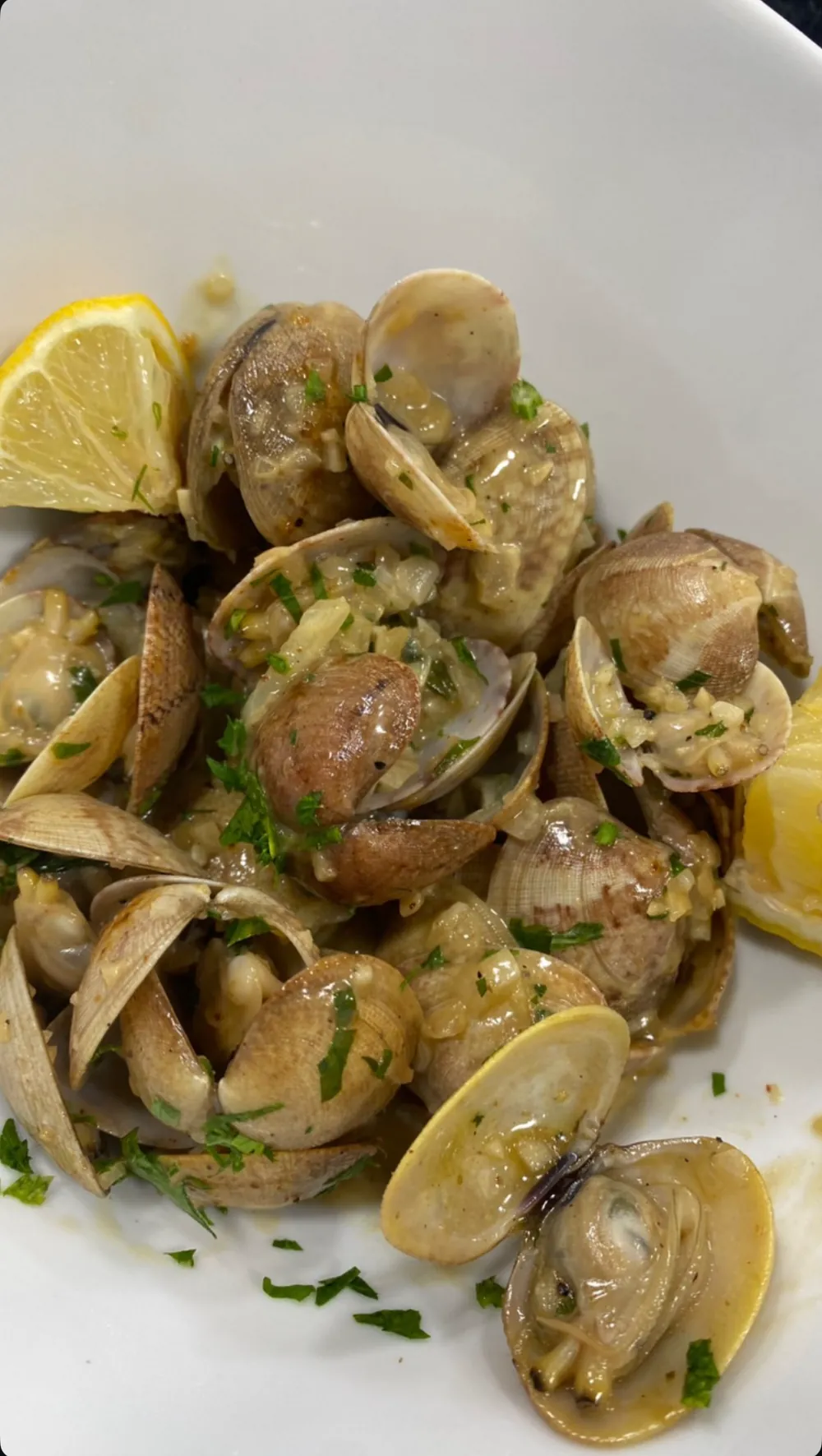Palourdes ouvertes dans leur jus à l'ail et au persil, quartier de citron